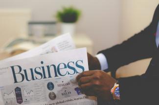 person wearing suit reading business newspaper by Adeolu Eletu courtesy of Unsplash.